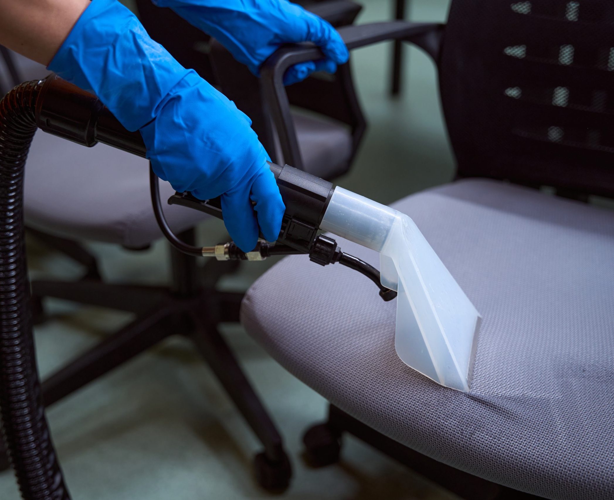 cleaner vacuuming chairs in an office