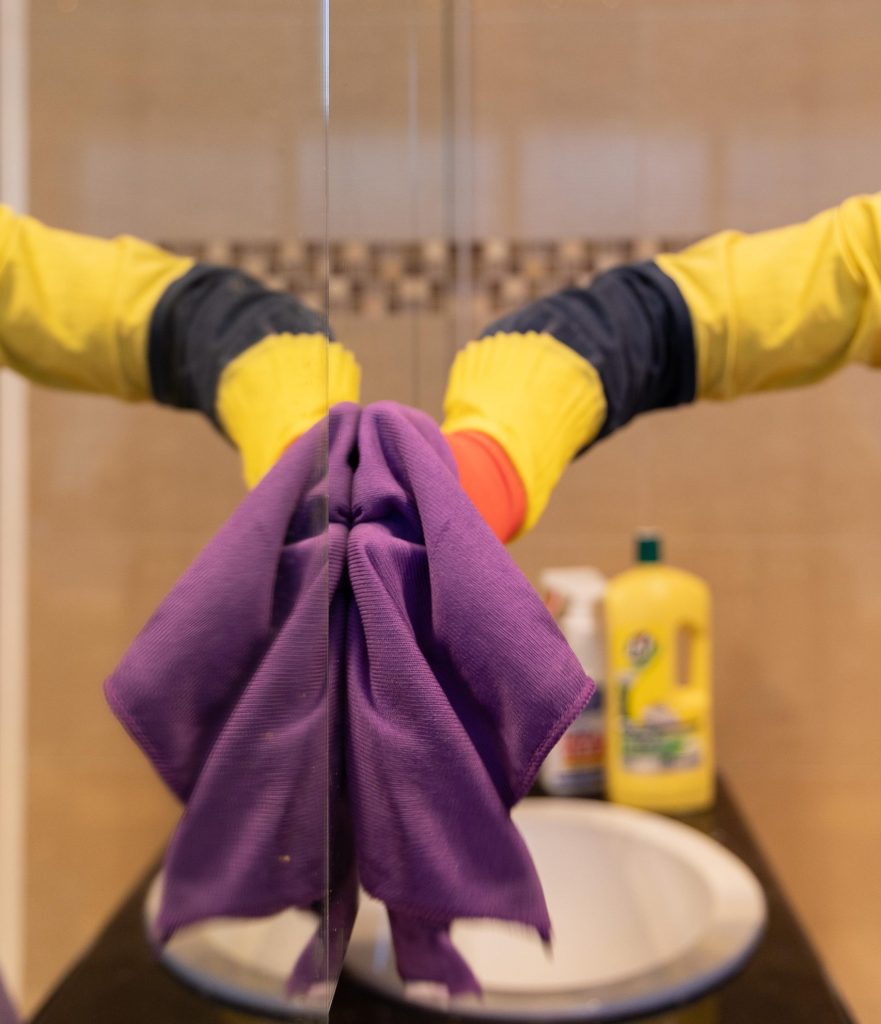 cleaner using a microfibre cloth on a mirror